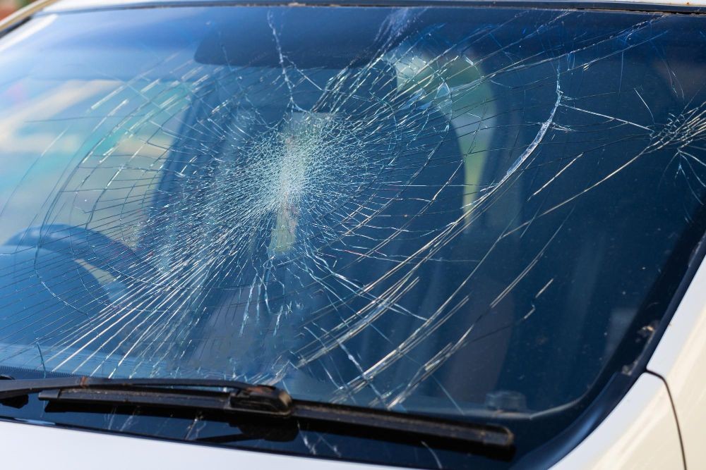 Close-up of a car windshield with extensive cracks and a large shattered area in the center.